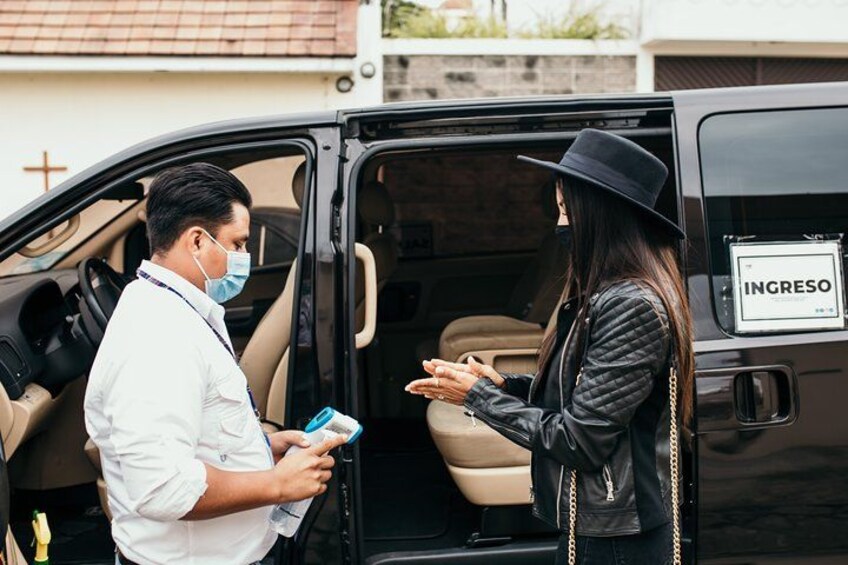A person in a white shirt and black hat standing next to a black van with a sign reading 'INGRESO'. 2