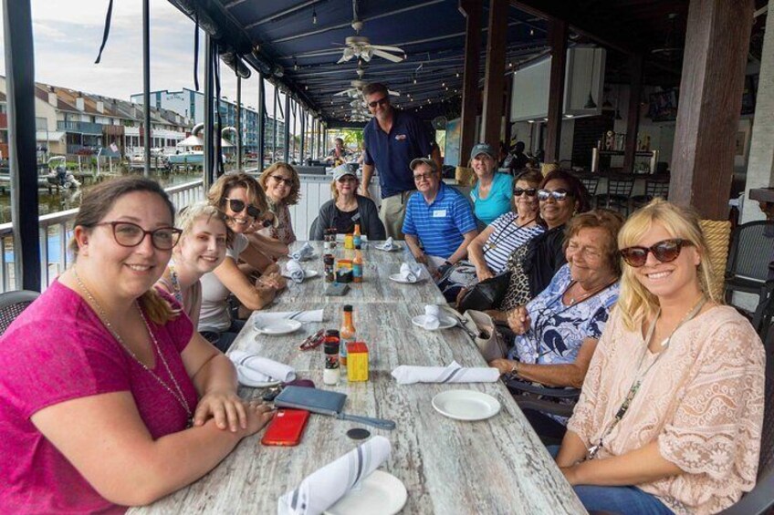 A group of people seated at an outdoor table with a view of the water. 5