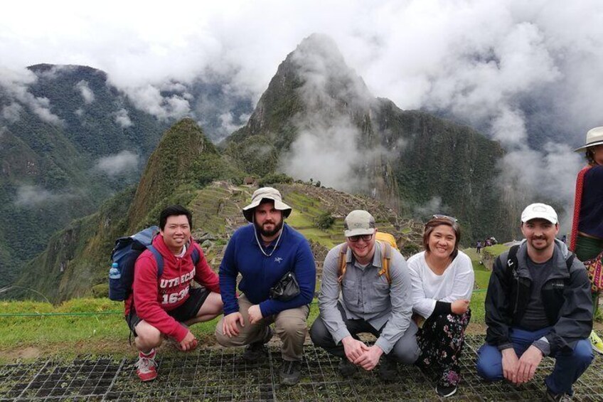 A group of hikers on a mountain trail with lush greenery and misty mountains in the background. 1