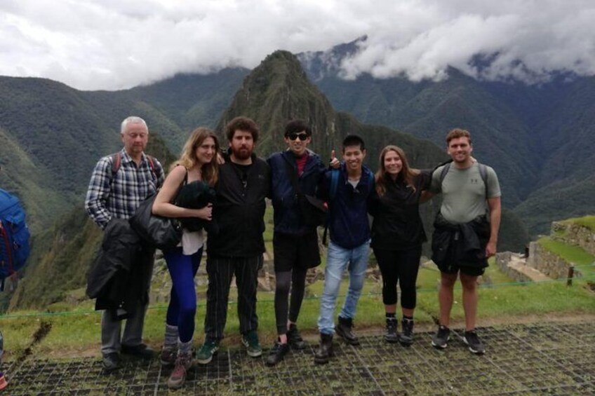A group of people standing on a grassy area with a mountainous landscape in the background. 5