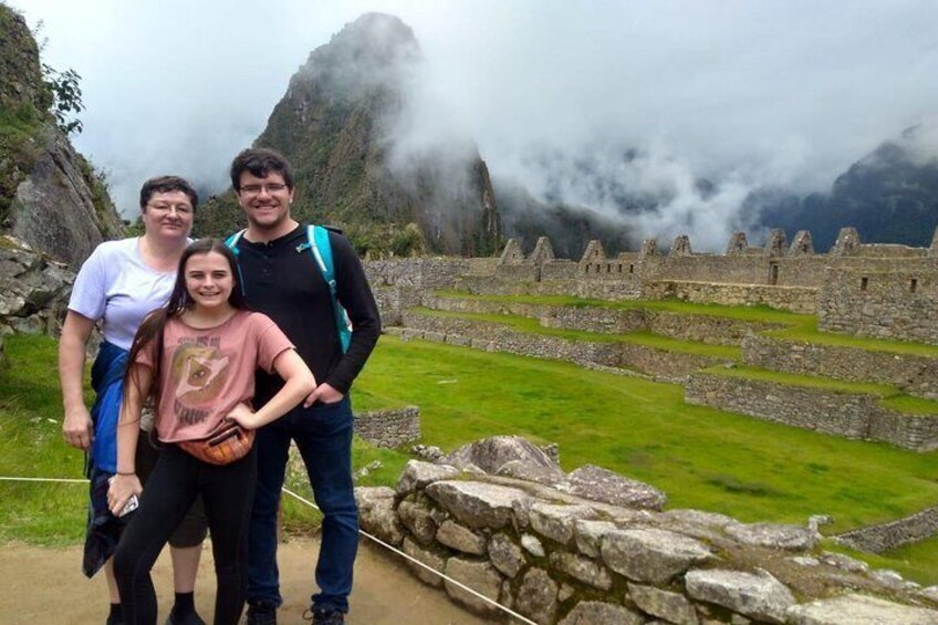 A family at Machu Picchu with ancient stone structures and misty mountains in the background. 4