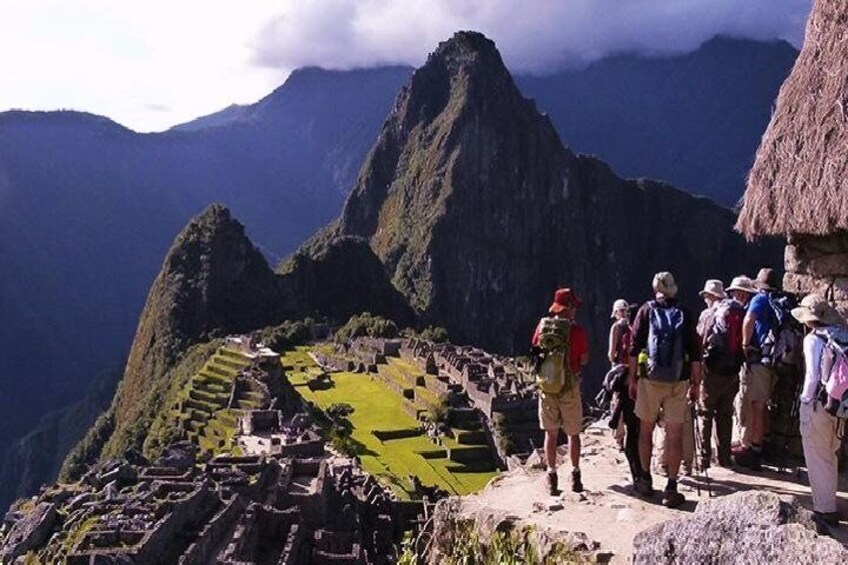 A group of hikers on a mountain trail with terraced fields and a prominent peak in the background. 3