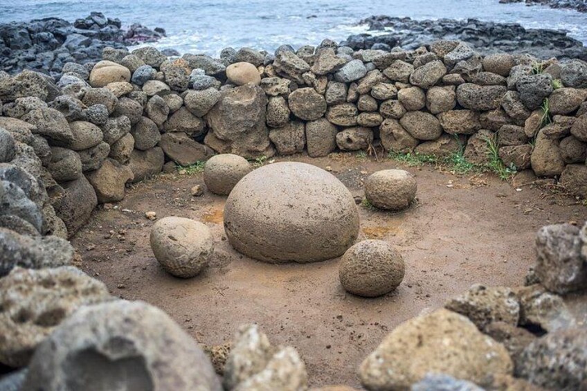 Un muro de piedra con grandes rocas y una zona arenosa al frente. 4