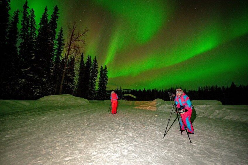 Deux personnes font du ski dans un paysage enneigé, avec des aurores boréales en arrière-plan. 5