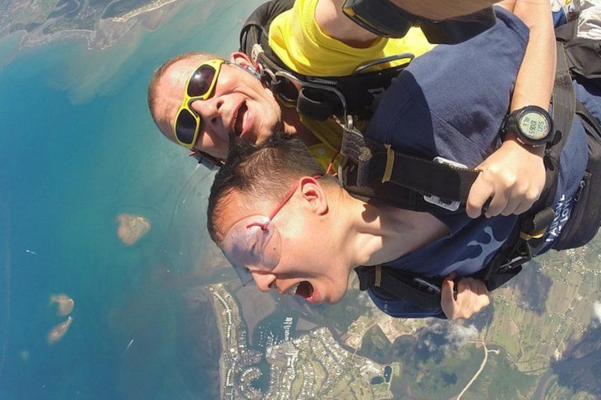 Two people skydiving with parachutes, above a coastal landscape. 4