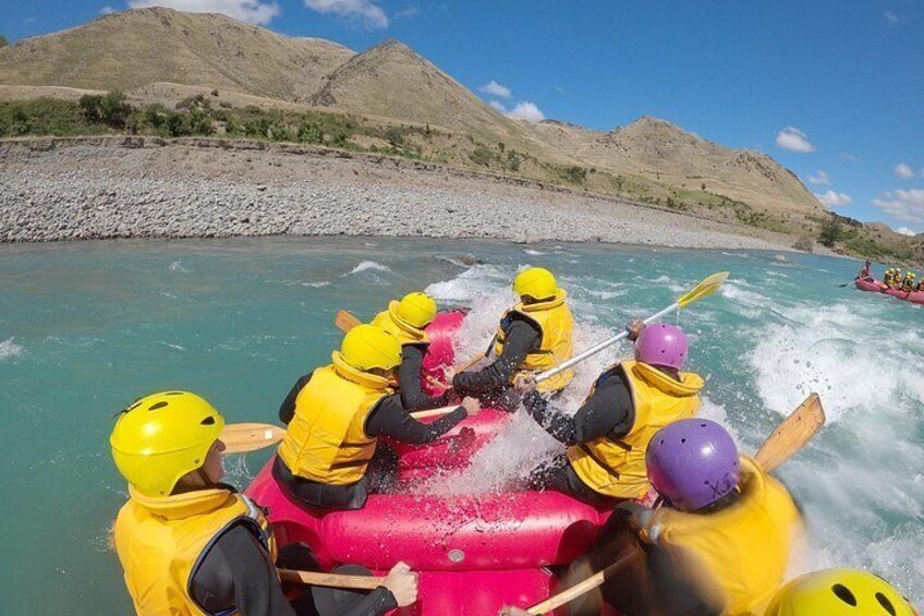 A group of people rafting on a river with clear water and mountainous terrain in the background. 4