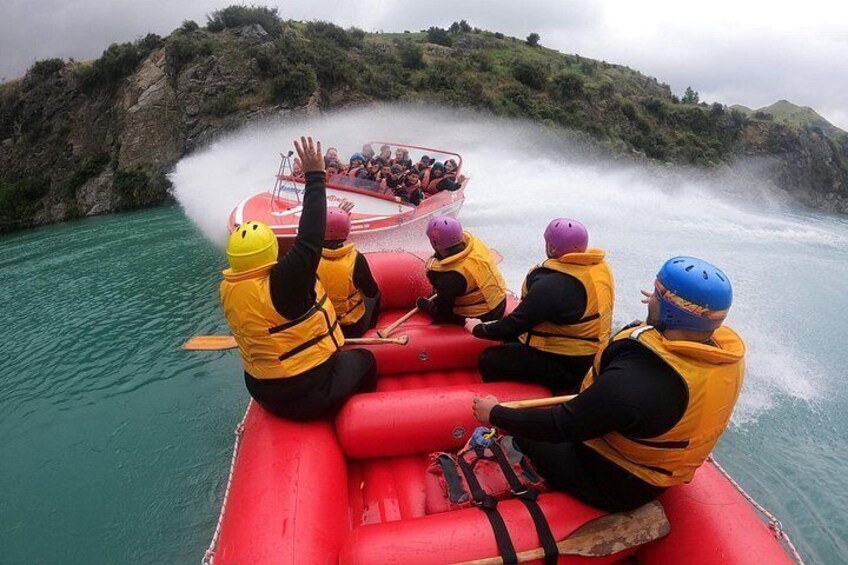 A group of people in a red inflatable raft on a river, wearing life jackets and helmets. 5