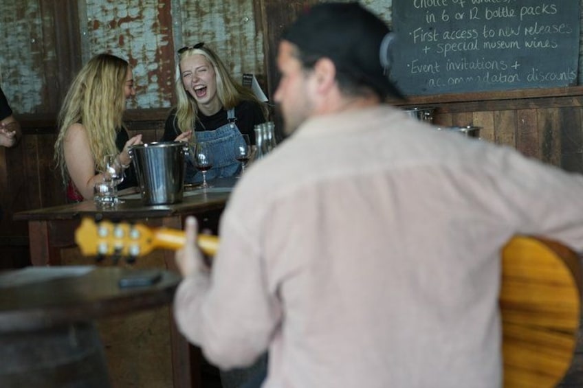 A bar with a chalkboard menu, a guitar, and people sitting at tables. 2