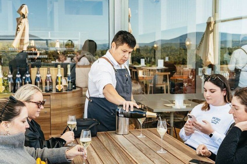 A group of people at a restaurant with a waiter pouring drinks. 2