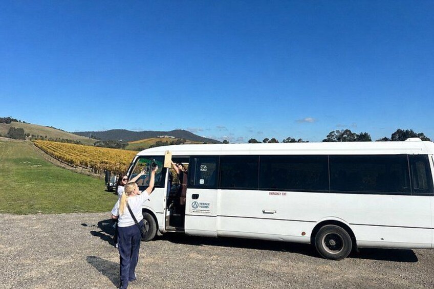 A white bus parked on a gravel road with a person boarding it. 3