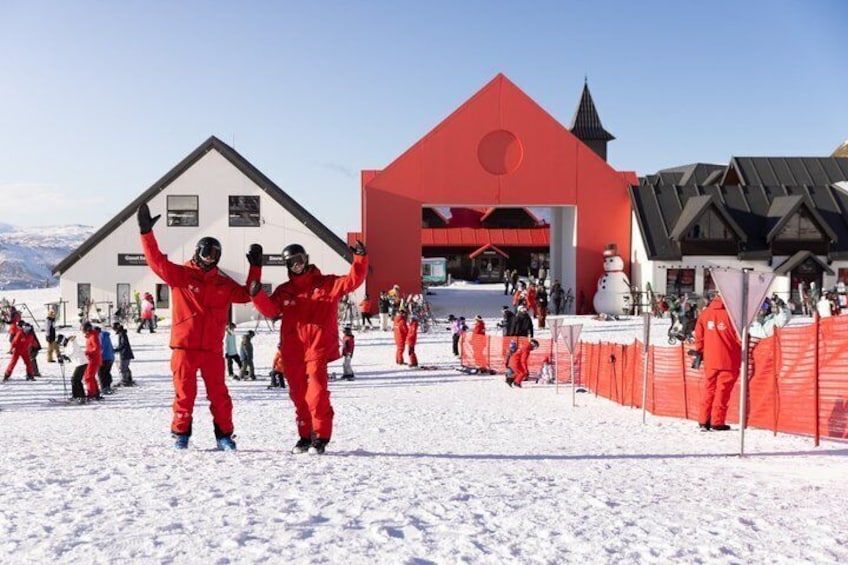 A snowy ski resort with red buildings and people skiing. 4