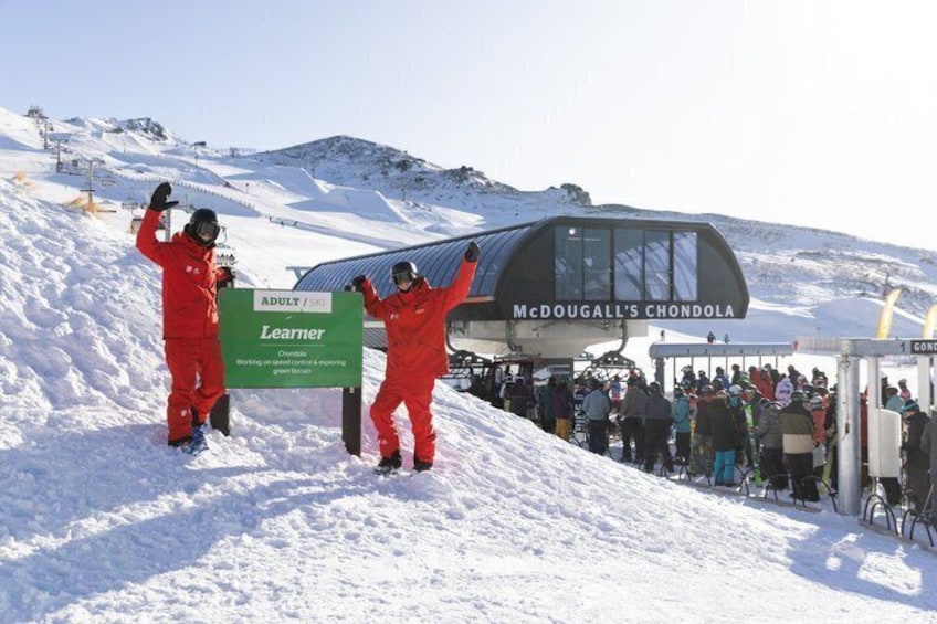 A ski lift at McDougall's Chondola with skiers in red suits. 1