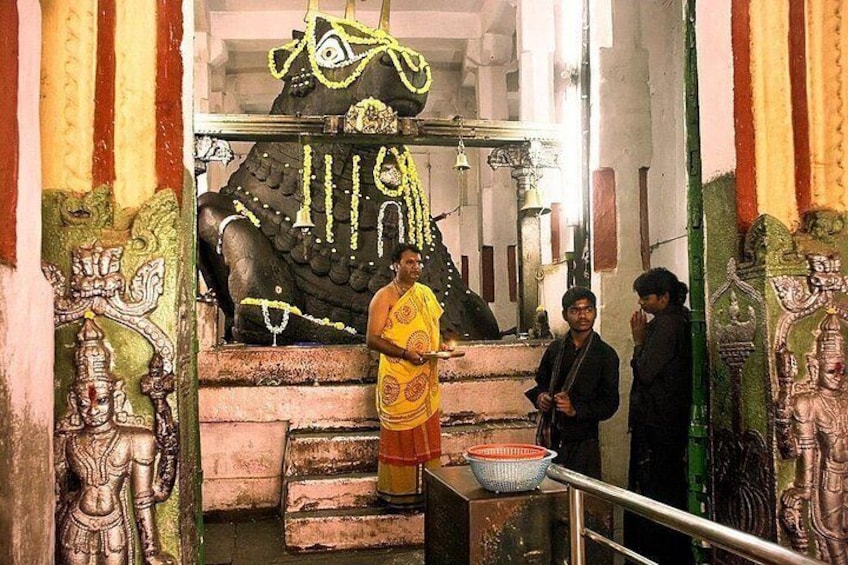 L’intérieur d’un temple, avec une grande statue, une personne vêtue d’un costume traditionnel et une autre personne portant des vêtements modernes. 2