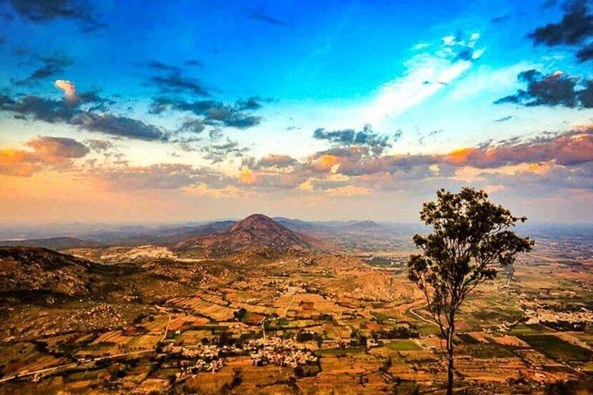 A mountainous landscape with a tree in the foreground and a village in the valley below. 4
