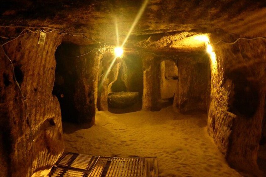 A cave with a wooden floor and stone walls, illuminated by a single light source. 5