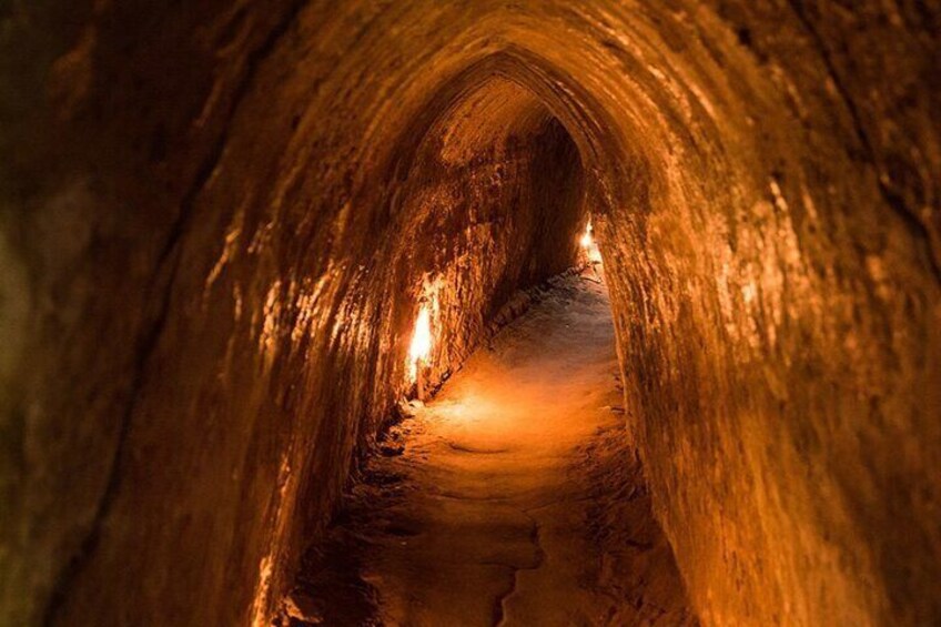 Interior view of the Cu Chi Tunnels, showcasing narrow, illuminated passageways lined with rough walls.