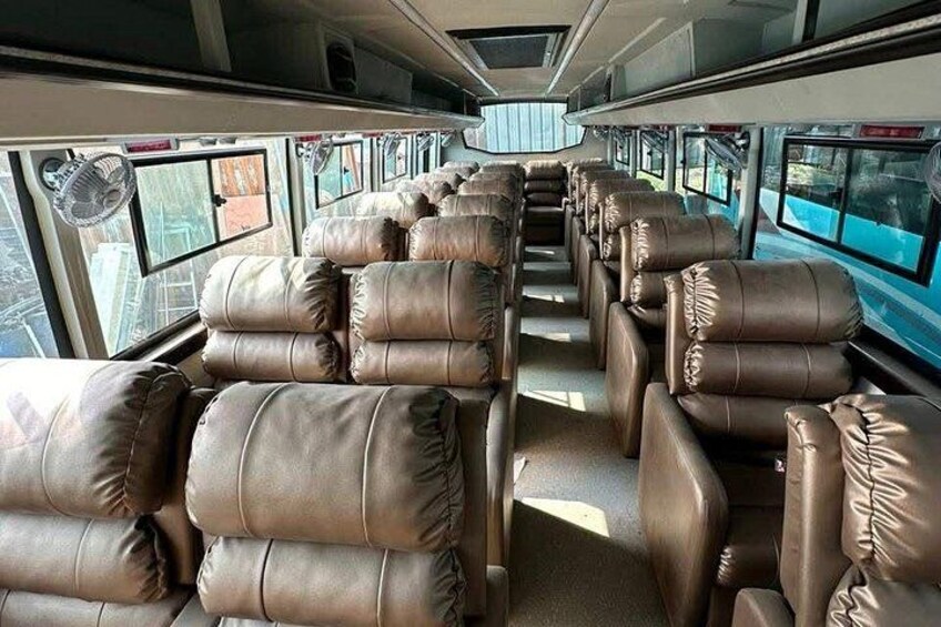 A train interior with leather seats, windows, and overhead luggage racks. 1