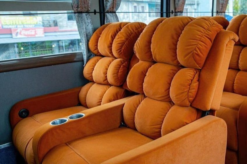 A row of orange cushioned seats with cup holders. 2