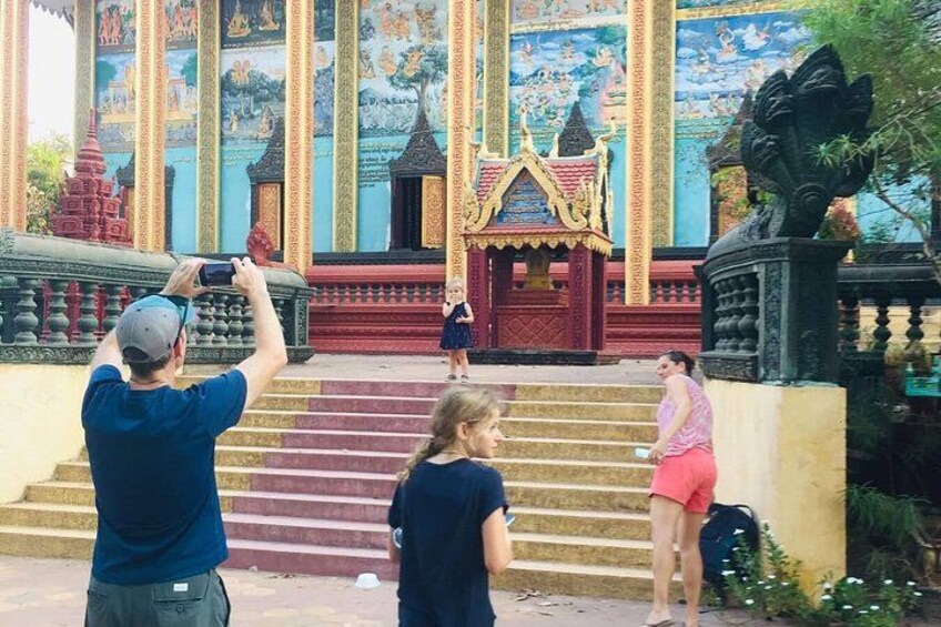 A temple with colorful murals, a red-roofed structure, and a statue. 1