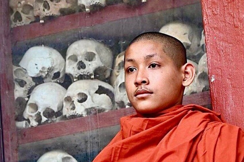 A person in a red robe standing in front of a wall with skulls. 1