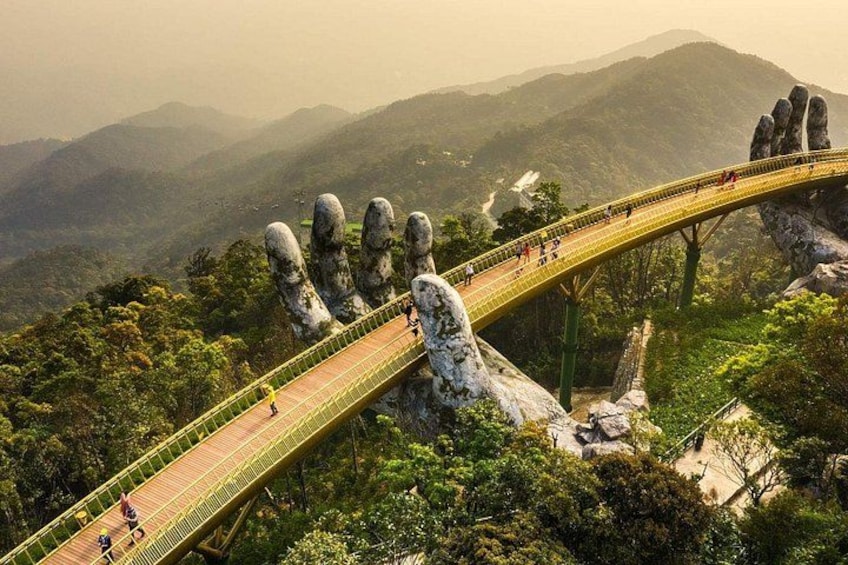 A bridge with a unique hand-shaped design, surrounded by lush greenery and mountains. 5