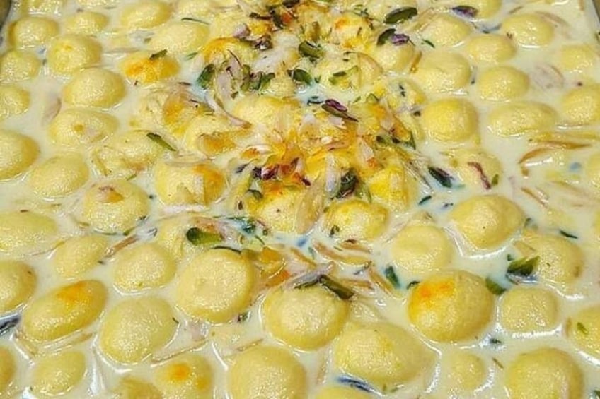 Primer plano de un postre cremoso con bolitas amarillas y un adorno de nueces picadas. 1