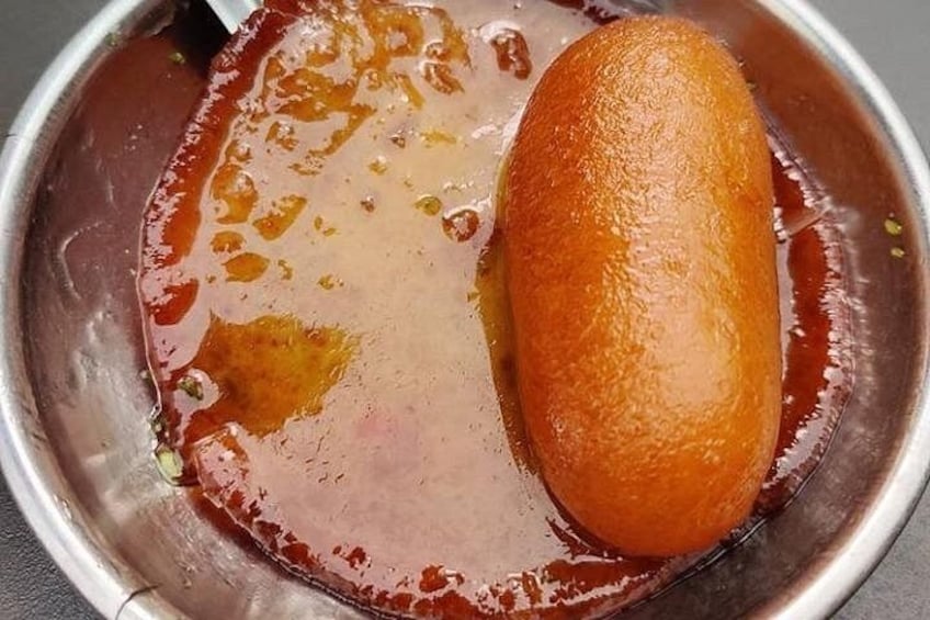 Un tazón de metal con un objeto dorado-café y un líquido marrón rojizo. 5