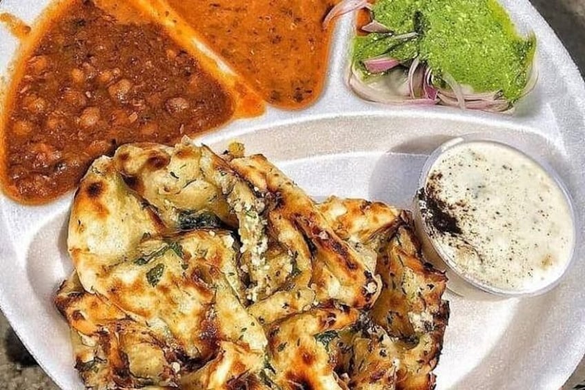 Un plato con pan naan, salsa roja, chutney verde y salsa blanca para mojar. 2
