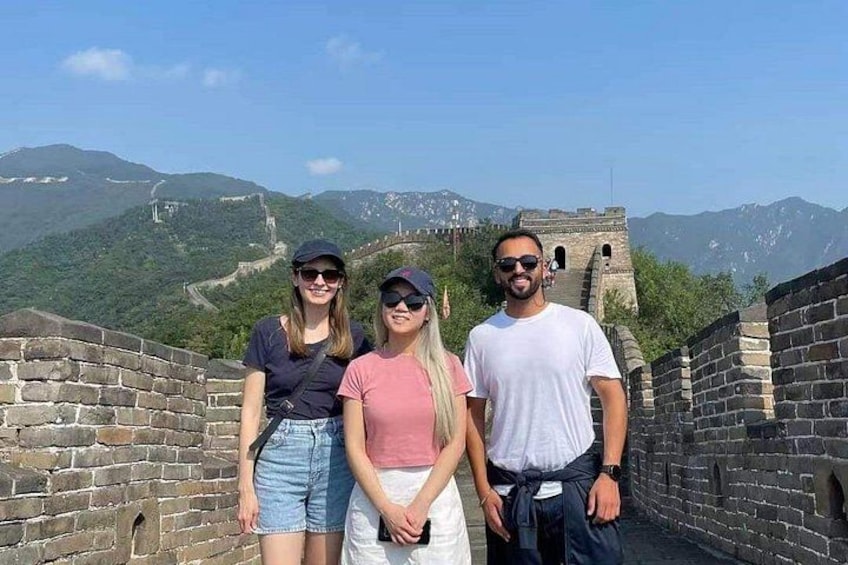 A group of people standing on the Great Wall of China with mountains in the background. 4