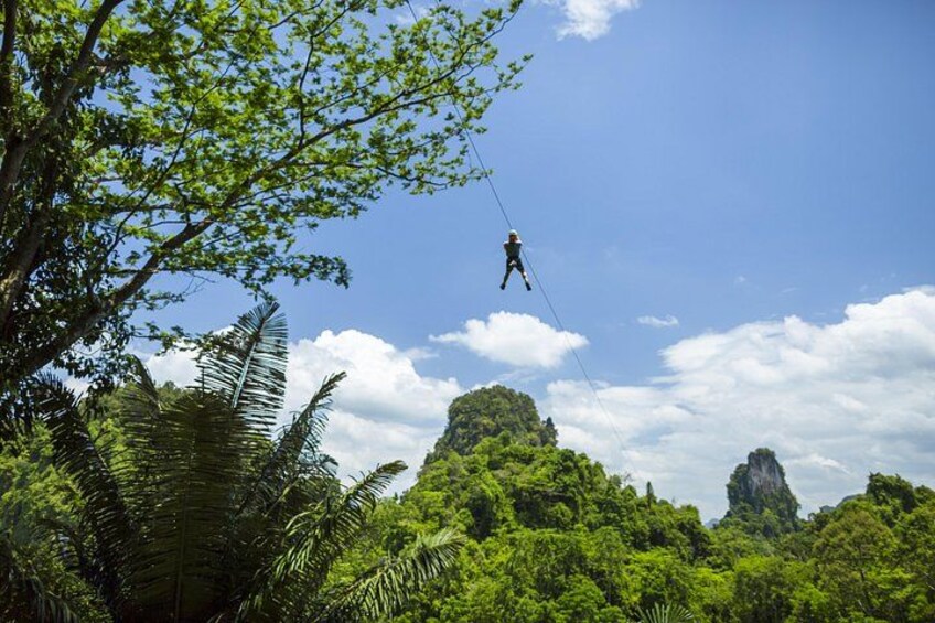 Una persona haciendo bungee jumping con una vista despejada de una vegetación exuberante y afloramientos rocosos al fondo. 1