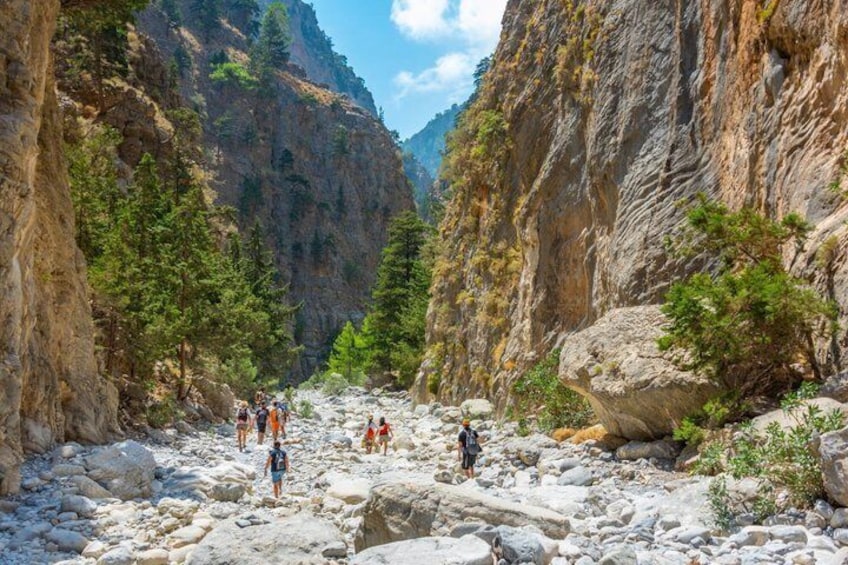 A rocky canyon with hikers and a river. 3