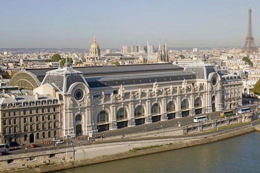 Un grand bâtiment historique surmonté d’un dôme, avec une rivière au premier plan et la Tour Eiffel en arrière-plan. 1
