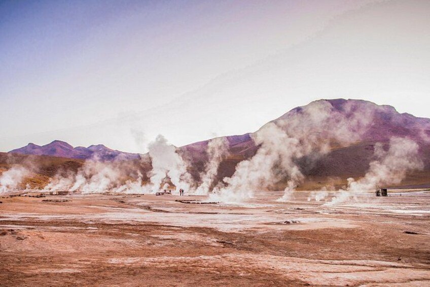 A geothermal area with steam vents and a mountainous backdrop. 2