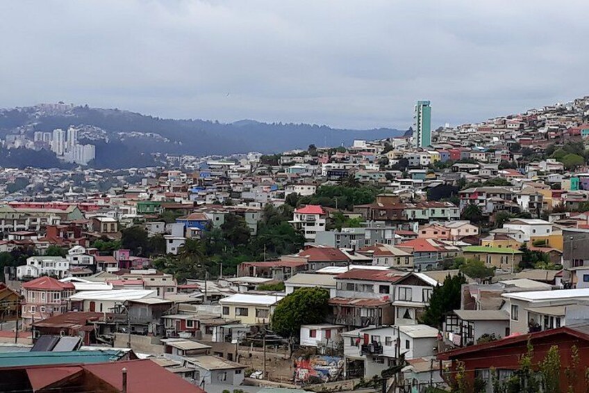 Une zone urbaine densément peuplée, avec un mélange de bâtiments résidentiels et un imposant gratte-ciel verdoyant qui se distingue à l’horizon. 4