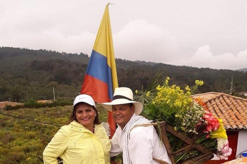 Two people standing outdoors with a flag and flowers. 2
