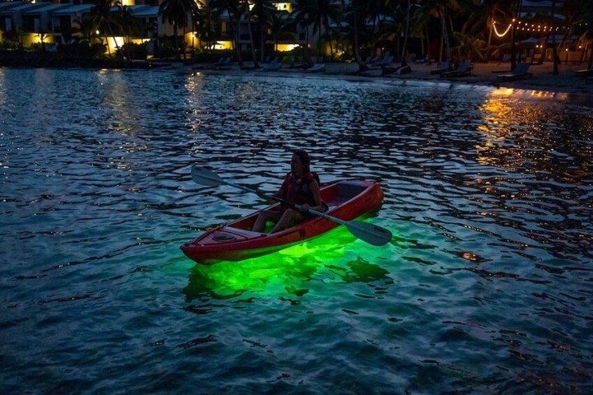 Una persona practica kayak en un cuerpo de agua por la noche con luces verdes iluminadas. 1