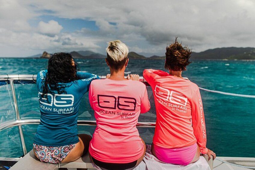 Three people on a boat wearing matching shirts with 'Ocean Surfari' and a number on the back. 2