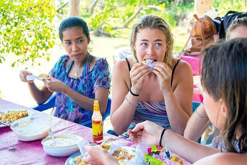 People sitting at an outdoor table with food and drinks. 4