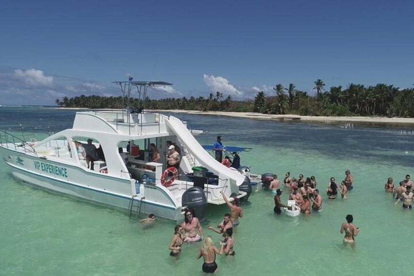 A boat with people swimming in the water and a beach in the background. 2
