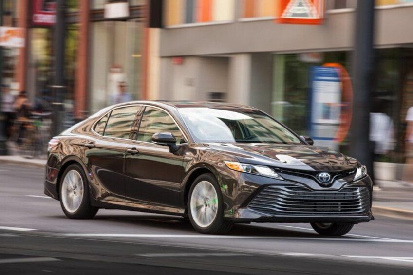 A dark-colored sedan driving on a city street. 3