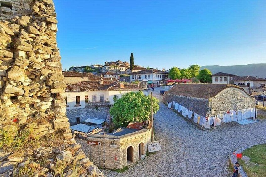 A historic town with stone buildings, cobblestone streets, and a prominent stone tower. 2