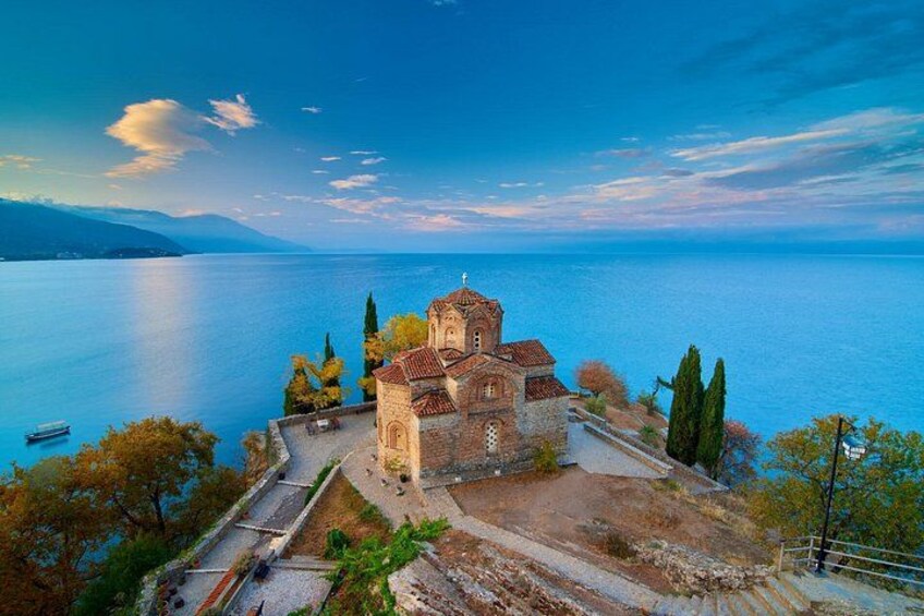 A church surrounded by trees and a body of water. 3