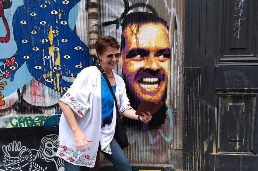 Una persona de pie frente a un muro cubierto de grafitis con un gran mural colorido. 4