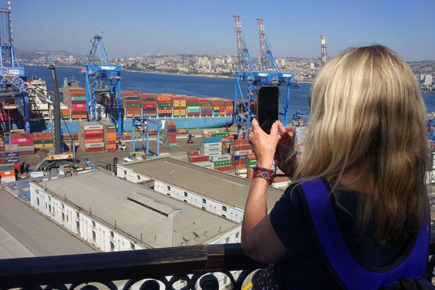 Un puerto con contenedores de carga, grúas y una persona tomando una fotografía. 2