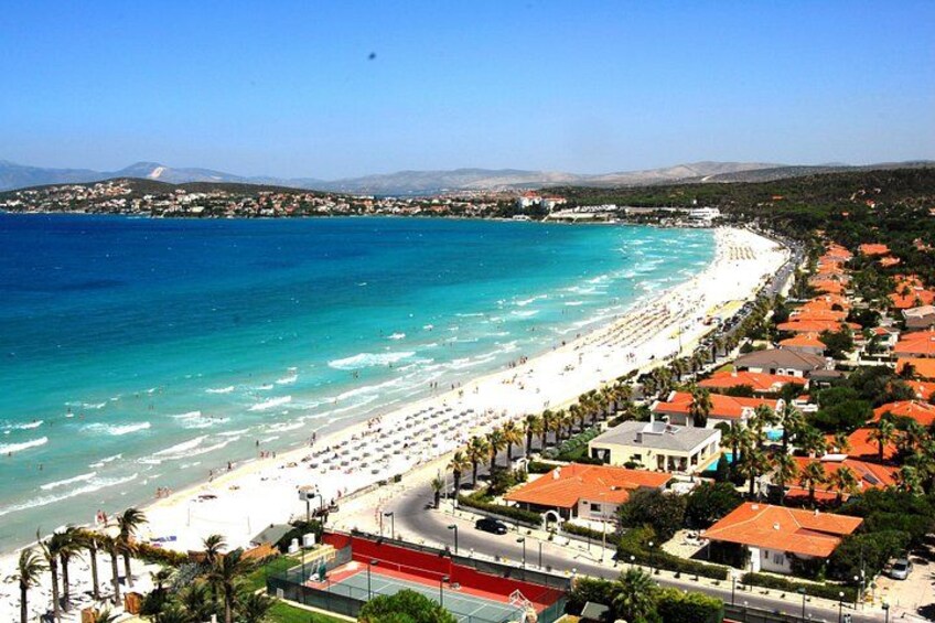Un pueblo costero con playa, casas de techo rojo y un mar azul cristalino. 2