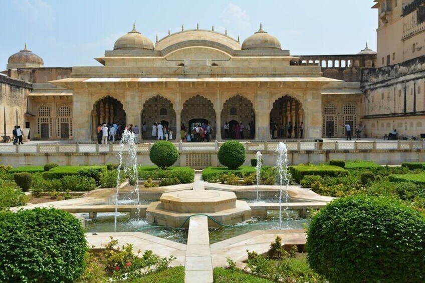 Un edificio storico con ingressi ad arco, una fontana centrale e giardini curati. 5