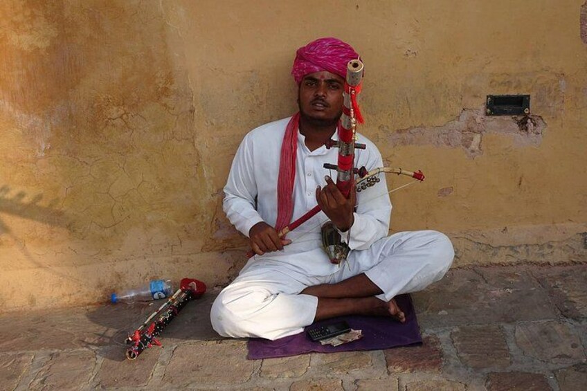 A person sitting on a mat, holding a musical instrument. 5