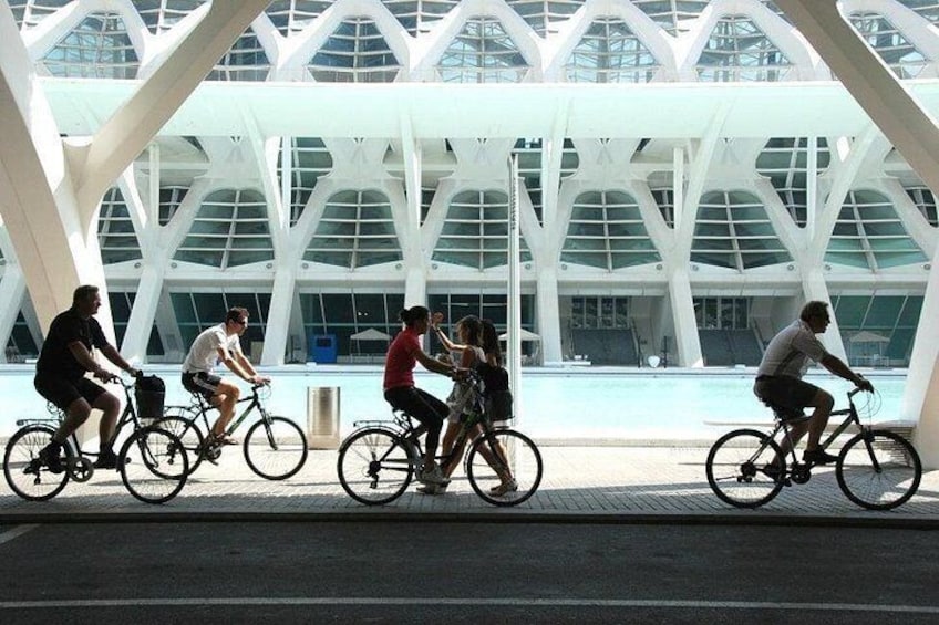 Des personnes à vélo circulent sous une structure architecturale moderne dotée d’un toit de verre. 4