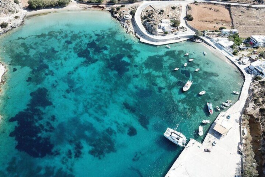 Vue aérienne d’une zone côtière avec des eaux turquoise et limpides, des bateaux amarrés le long de la côte et une digue incurvée. 5