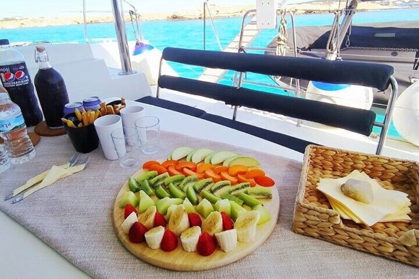 Une table avec un assortiment de fruits, un panier de pain et une bouteille d’eau, le tout sur un bateau. 4